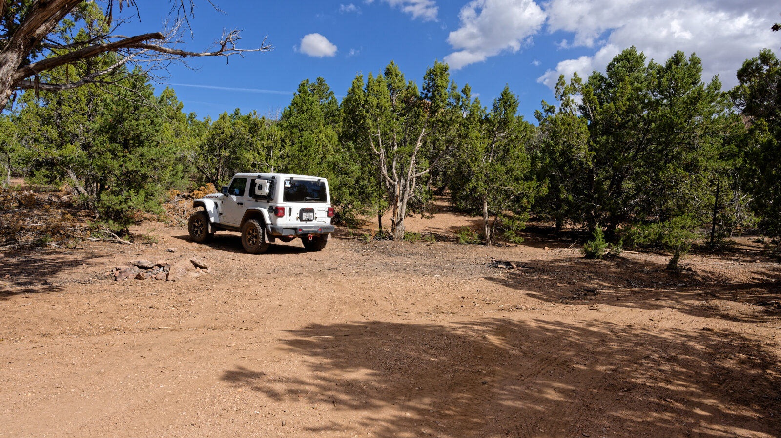 Camping spot for one or two small rigs or small trailers. It has shade but is not private, and it sits next to an ATV trail.